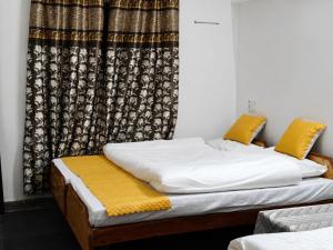 two twin beds in a room with a curtain at Hotel Dharali Nature In Dharali in Gangnāni