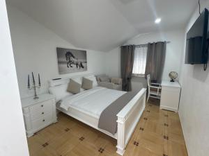 a white bedroom with a bed and a chair at Herz Apartmani in Igalo