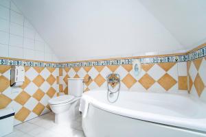 a bathroom with a white tub and a toilet at Gastland M1 Hotel & Conference Center in Páty