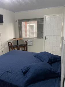 a bedroom with a bed and a table with chairs at Pousada Coral in Osório