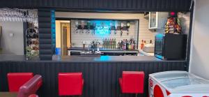 a bar with red chairs in front of it at Glamping Hut - Sleeps up to 4 Hot Tub & Parking in Welshpool