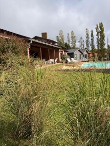a house with a field of tall grass in front of a house at Quinta Ecuador Tandil in Tandil