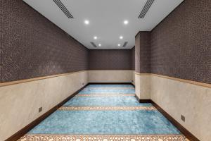 an empty room with brown walls and blue carpet at Grand Millennium Al Haram Hotel in Medina