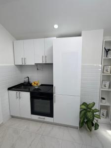 a kitchen with white cabinets and a black appliance at Herz Apartmani in Igalo +13 photos