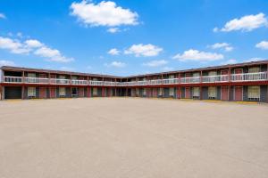 a large red building with a large parking lot at Valley Motel Corpus Christi Near Airport I 37 in Corpus Christi