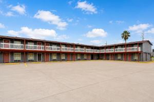 a large red building with a large parking lot at Valley Motel Corpus Christi Near Airport I 37 in Corpus Christi