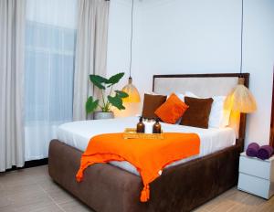 a bedroom with a bed with an orange blanket on it at Boha Zanzibar Beach House in Bwejuu