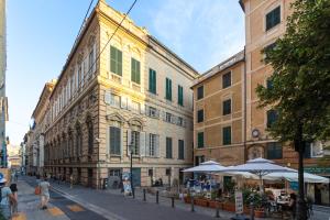 a group of buildings with tables and umbrellas on a street at Nik apartment in Genoa
