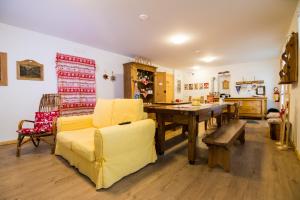 uma sala de estar com um sofá amarelo e uma mesa em Olimpic Hostel em Schilpario
