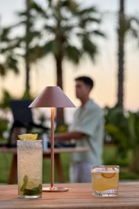 a drink on a table with a small lamp on it at Avali, Mar-Bella Collection in Agios Ioannis Peristerion
