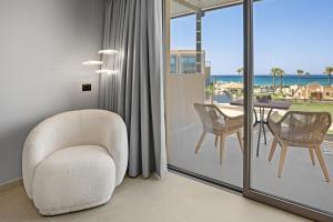 a living room with a chair and a balcony with a table at Ventale Island Breeze Resort in Georgioupolis