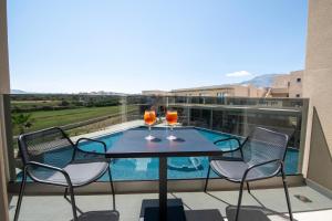 a balcony with a table and chairs and a pool at Ventale Island Breeze Resort in Georgioupolis