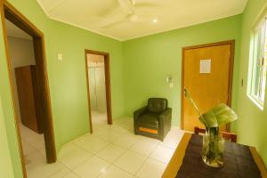 a living room with green walls and a chair at Complejo de Apartamentos parque naturaleza in Encarnación