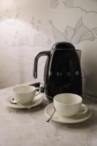 two cups on plates next to a tea kettle at Lumen in Kostanay