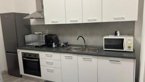 a kitchen with white cabinets and a microwave and a sink at FaZi Home in Cosenza +25 photos