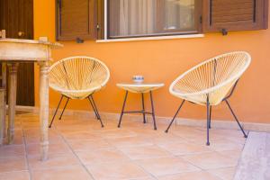 two chairs and a table in front of a wall at Solemar Sicilia - Le Casette Di Calzata in Campofelice di Roccella