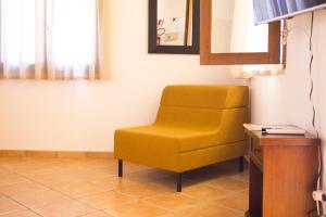 a yellow chair in a room with a table at Solemar Sicilia - Le Casette Di Calzata in Campofelice di Roccella
