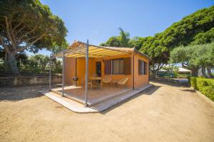 a small house with a porch and a table at Solemar Sicilia - Le Casette Di Calzata in Campofelice di Roccella