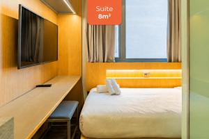 a hotel room with a bed and a desk and a sign at Linked Batel Curitiba by Xtay in Curitiba