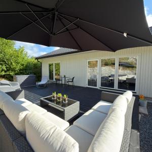 a patio with white couches and a black umbrella at Orrvägen in Torshälla