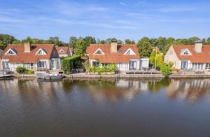 a group of houses on the shore of a lake at Cozy Waterfront Getaway for a Perfect Holiday in Langweer