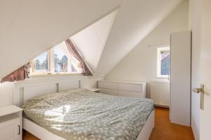 a white bedroom with a bed and a window at Cozy Waterfront Getaway for a Perfect Holiday in Langweer