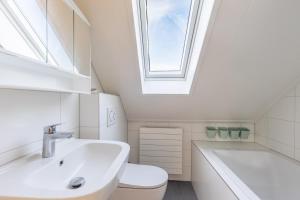 a bathroom with a sink and a toilet and a window at Cozy Waterfront Getaway for a Perfect Holiday in Langweer +28 photos