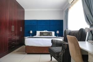 ein Schlafzimmer mit Bett, Schreibtisch und Stühlen in der Unterkunft The GL in Gaborone