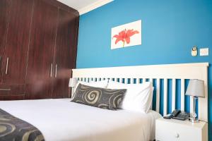 ein Schlafzimmer mit einem weißen Bett und einer blauen Wand in der Unterkunft The GL in Gaborone + 3 Fotos