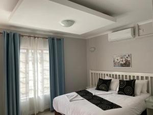 ein Schlafzimmer mit einem Bett und einem Fenster in der Unterkunft The GL in Gaborone