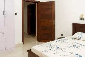 a bedroom with a bed and a wooden door at Chamacohouse in Cotonou