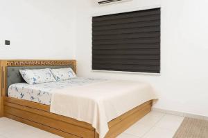 a bedroom with a bed and a window with black shutter at Chamacohouse in Cotonou