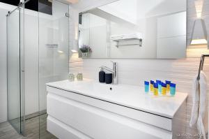 a white bathroom with a sink and a shower at מקום טוב באמצע במושבת כנרת in Kinneret +7 photos