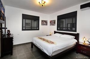a bedroom with a large bed and two windows at מקום טוב באמצע במושבת כנרת in Kinneret