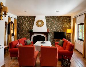 a living room with red chairs and a fireplace at Aromas del Raposo in Puebla de Sancho Pérez
