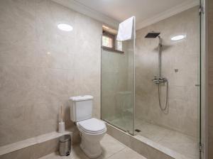 a bathroom with a toilet and a glass shower at Taugul Hotel in Almaty +5 photos