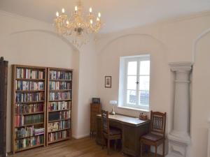 a library with a desk and bookshelves and a chandelier at Schlossgut Franken in Redwitz an der Rodach