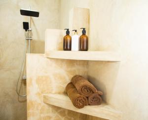 a bathroom with three bottles and towels on a shelf at Boha Zanzibar Beach House in Bwejuu +84 photos
