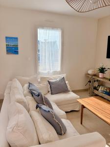 a living room with a white couch and a table at Maison de la plage - Dossen Santec - Réservations à la semaine, de week-ends en week-ends in Santec