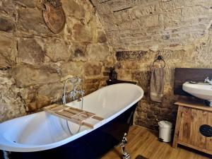 a bath tub in a stone bathroom with a sink at Schlossgut Franken in Redwitz an der Rodach +71 photos