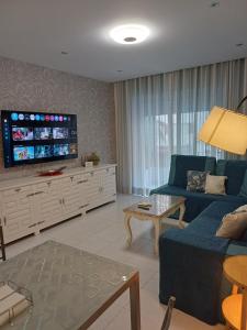 a living room with a blue couch and a flat screen tv at La Fuente apartamento con 3 AC in Gandía
