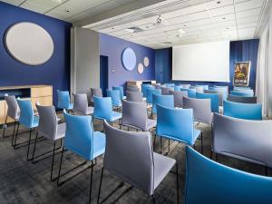 a room with blue chairs and a white screen at ibis Styles Katowice Airport in Pyrzowice
