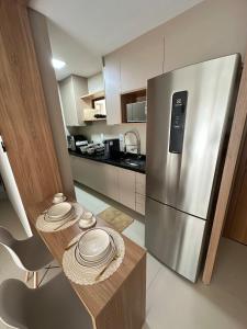 a kitchen with a table and a stainless steel refrigerator at Novíssimo Altiplano 3 Quartos e Lazer Completo in João Pessoa