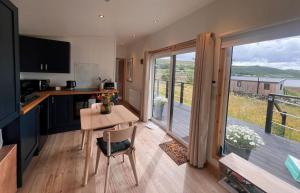 a kitchen with a table and a view of a balcony at Tiny Mara in Uig