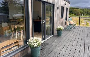 a porch with two potted plants on a deck at Tiny Mara in Uig +2 photos