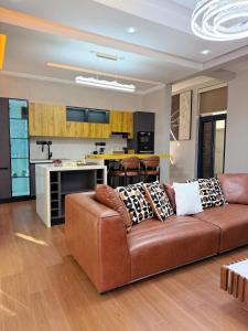 a living room with a brown couch and a kitchen at Roses Villa at Elysium Home in Dodoma