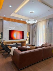 a living room with a brown couch and a tv at Roses Villa at Elysium Home in Dodoma