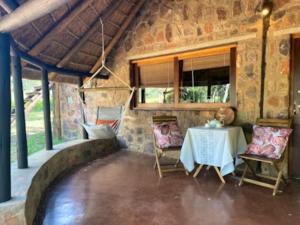 a table and chairs in a room with a stone wall at Palala River Cottages in Vaalwater