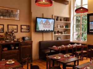 a dining room with tables and a tv on the wall at Hôtel Les Trois Luppars in Arras
