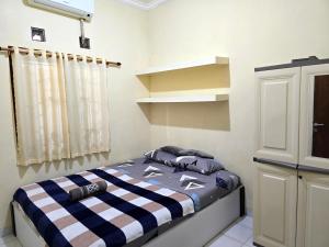 a bedroom with a bed with a checkered blanket at M2 Homestay Jogja in Jarakan